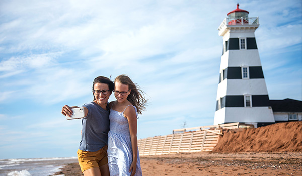 Woman and daughter taking a selfie in front of a lighthouse.