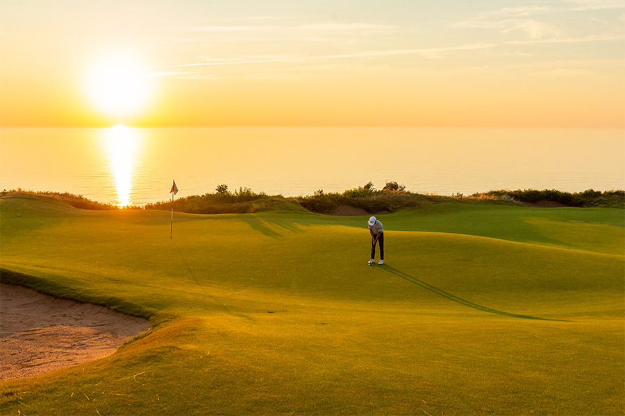 Golfer at Cabot Cliffs with the sun setting behind.
