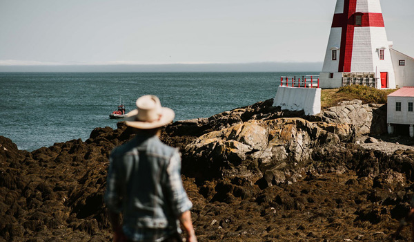View of a person looking at the ocean by a lighthouse.
