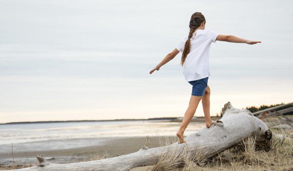 Girl walking on driftwood on a beach in Caraquet.
