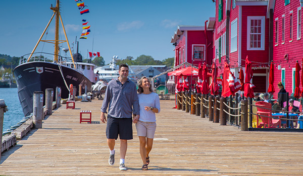 A couple walking along the pier with shops in the background