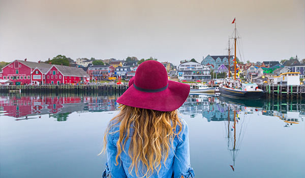 A woman in a red hat looking across the harbour to the town of Lunenburg